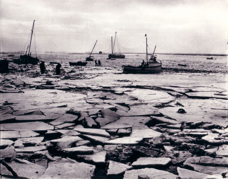  The severe winter 1962-63 at West Mersea Hard looking out towards the Packing Shed and the river. Wherever possible boats were brought ashore and any wooden boats left in the creeks suffered in the ice. 
Cat1 Mersea-->Old City & the Hard Cat2 Weather Cat3 Mersea-->Creeks, fleets, channels, saltings